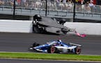 The car driven by Kyle Kirkwood, top, flips over after a crash in the second turn during the Indianapolis 500 auto race at Indianapolis Motor Speedway