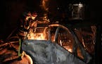 Emergency workers extinguish a fire in a parked car, caused by falling debris from the latest aerial Russian attack in the Pecherskyi district of Kyiv