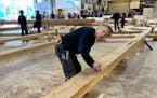 Peter Henrikson, 61, a timber framer from Grand Marais, Minn., measures a beam, part of the new roof of the Notre Dame cathedral de Paris, Thursday, M
