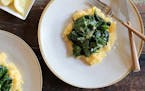 A sauté of spinach, lemon and garlic is served over polenta before being topped with Parmesan cheese.