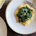 A sauté of spinach, lemon and garlic is served over polenta before being topped with Parmesan cheese.