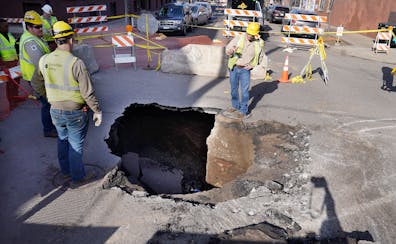 On April 10, utility workers surrounded a sinkhole roughly 10 feet deep and 5 feet wide that opened up in the middle of the intersection of W. 27th St