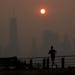A man runs in front of the sun rising over the lower Manhattan skyline in Jersey City, N.J., Thursday, June 8, 2023. Intense Canadian wildfires are bl