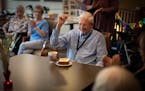 Richard King raises his fist in cheer as he is served a piece of carrot cake while celebrating turning 100 with fellow residents and staff at his home