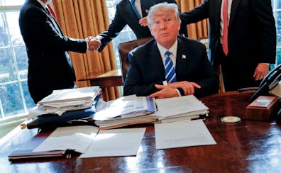 President Donald Trump at his desk after a meeting with Intel CEO Brian Krzanich, left, in the Oval Office, Feb. 8, 2017. A lockbag is visible, the ke