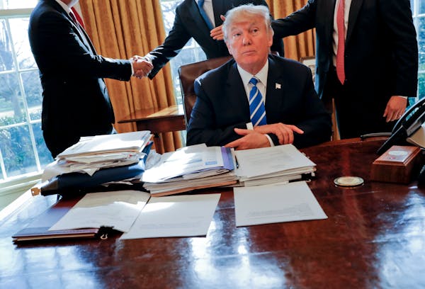 President Donald Trump at his desk after a meeting with Intel CEO Brian Krzanich, left, and members of his staff in the Oval Office in Washington, Feb
