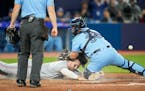 Ryan Jeffers scored on a sacrifice fly by Michael A. Taylor, while Blue Jays catcher Alejandro Kirk makes a tag without the ball during the 10th innin