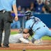 Ryan Jeffers scored on a sacrifice fly by Michael A. Taylor, while Blue Jays catcher Alejandro Kirk makes a tag without the ball during the 10th innin