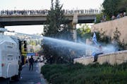 Israeli police use a water cannon to disperse demonstrators blocking a road during a protest against plans by Prime Minister Benjamin Netanyahu’s go