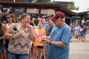 Gov. Tim Walz paused outside the Nordic Waffle booth to show his bacon-wrapped waffle dog to a fairgoer waiting in line.