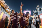 Gophers punter Mark Crawford and kicker Dragan Kesich exit the Huntington Bank field after defeating Nebraska 13-10 on Thursday