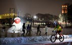 A cyclist rode past a Walker guided snowshoe tour group on a January evening at the Minneapolis Sculpture Garden.