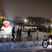 A cyclist rode past a Walker guided snowshoe tour group on a January evening at the Minneapolis Sculpture Garden.