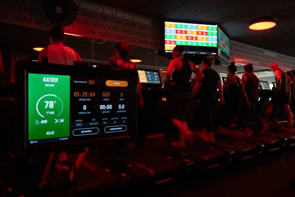 A display on a rowing machine and overhead screen showed individual heart rates and more as people worked out at Orangetheory in Edina. 
