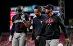 Royce Lewis, left, walked to the Twins’ dugout Tuesday night with assistant trainer Masa Abe and acting manager Jayce Tingler.