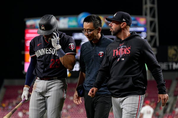 Royce Lewis, left, walked to the Twins’ dugout Tuesday night with assistant trainer Masa Abe and acting manager Jayce Tingler.