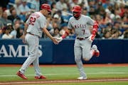 Angels’ Jo Adell (7) celebrates a home run with third base coach Bill Haselman (82) Thursday, Sept. 21, 2023, in St. Petersburg, Fla.