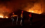 FILE - Firefighters monitor as flames consume brush along Gilman Springs Road during the Rabbit Fire, July 14, 2023, in Moreno Valley, Calif. More Ame