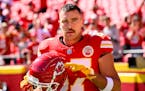 Kansas City Chiefs tight end Travis Kelce points to the Chiefs decal on his helmet as fans cheer during warmups before an NFL football game against th