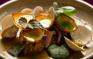 At Herbst, chef Eric Simpson prepares the pork chop with marinated clams.