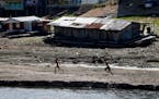 Boys walked next to a floating home stranded on what used to be the water´s edge of the Negro river, amidst a drought in Manaus, Brazil, Tuesday, Sep