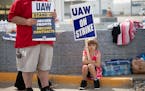 A young supporter holds a sign as United Auto Workers members strike at the Ford Michigan Assembly Plant on Sept. 16, 2023, in Wayne, Michigan.