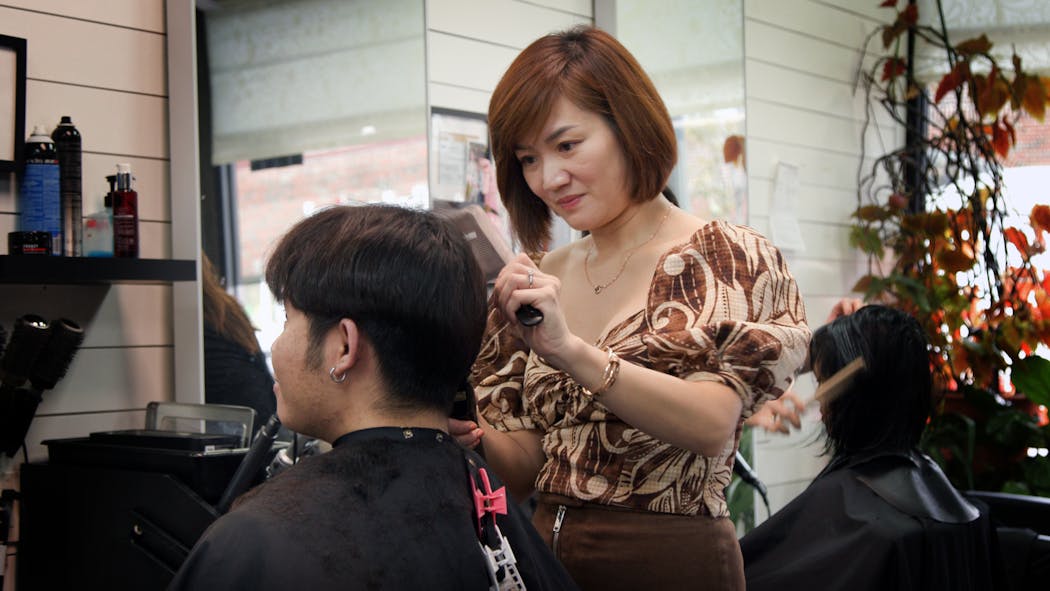 Kim Huynh, owner of Mai Hoa Beauty Salon, trims the hair of Peter Nguyen, 28. About four months ago, Nguyen got his first “soft perm,” which subtly added volume to his very straight hair. Nguyen, of Cottage Grove, said he trusts “only her,” referring to Huynh, with his tresses.