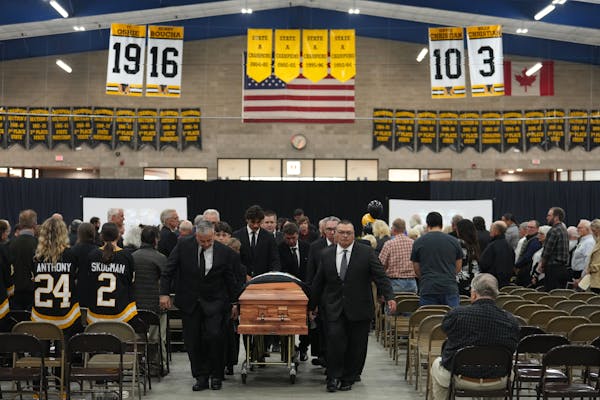 Pallbearers carried the casket of Henry Boucha out of the Gardens Arena as his high school uniform number, 16, hung from the rafters following his fun