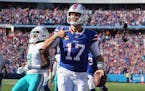 Bills quarterback Josh Allen celebrated in the end zone in front of Dolphins safety Jevon Holland, left, after scoring a touchdown Sunday.