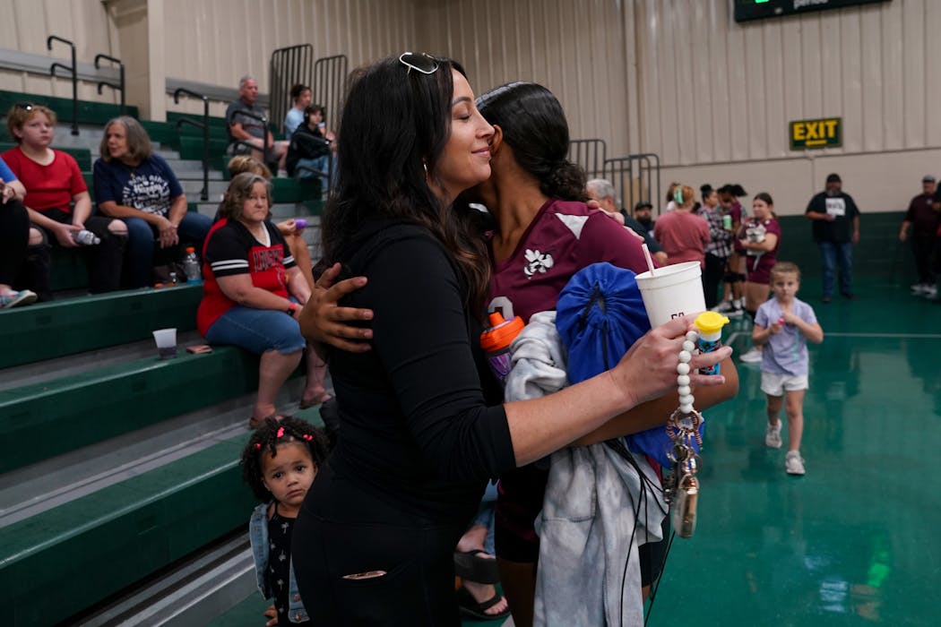 Desirae Holloway, with her 2-year-old daughter, Aliana, hugs her 13-year-old daughter, Ahmya, at Ahmya’s volleyball game in Louisville in September.