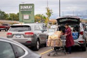 A Cub Foods shopper loads her car as the Sun Ray Shopping Center’s sign looms over its a half-full parking lot on in St. Paul, Minn., on Wednesday, 