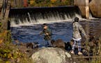 Siblings Silus Yang, 6, left, and Meverick Yang, 10, right, fish from the Hinckley Dam on the Grindstone River in Hinckley, Minn., on Tuesday, Oct. 17