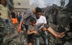 A Palestinian carries a child pulled out of a building hit in the Israeli bombardment of the Gaza Strip in Rafah, Oct. 22.