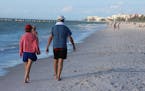 Vacationers walked along the beach in Naples, Fla.