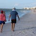 Vacationers walked along the beach in Naples, Fla.