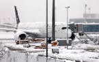A Lufthansa aircraft is parked at the snow-covered Munich airport, Germany, Saturday, Dec. 2, 2023. 