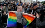 FILE - A gay rights activist stands with a rainbow flag, in front of journalists, during a protesting picket at Dvortsovaya (Palace) Square in St. Pet