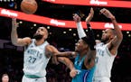 Hornets forward Brandon Miller, middle, vies for the ball with Timberwolves center Rudy Gobert, left, and forward Troy Brown Jr. during the first half